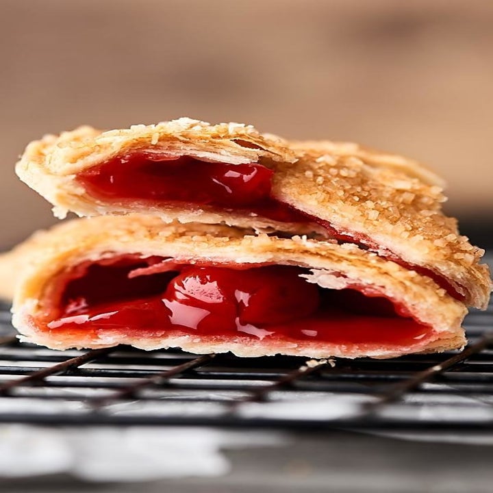 An up-close shot of a cherry-filled hand pie sliced into two pieces.