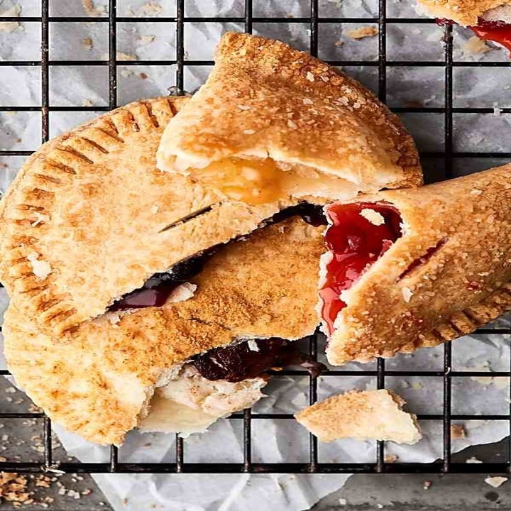 Little pieces of hand pies stuffed with different fruit fillings on a wire rack.
