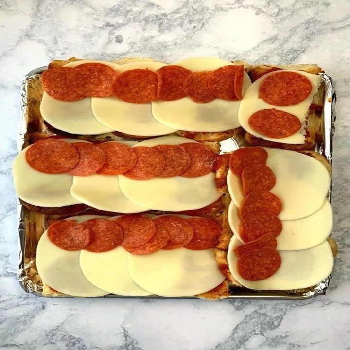 Burger buns topped with mozzarella, tomato sauce, and pepperoni.